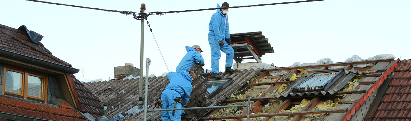 Dachdecker mit blauen Schutzanzügen decken Steildach in Hamm mit Asbestfaserzementplatten ab
