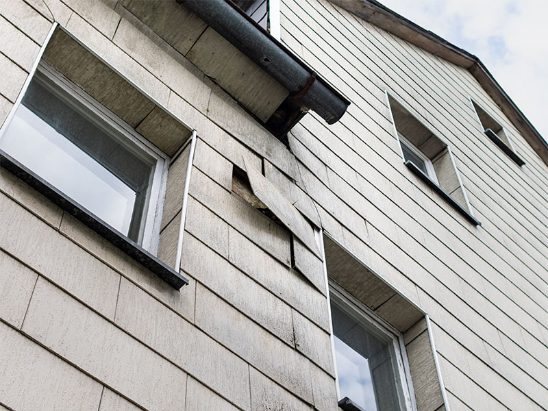 Großaufnahme Mehrfamilienhaus mit grauen Faserzementplatten an der Hausfassade die teilweise defekt und mit Asbest verseucht sind vor einer Fassadensanierung in Hamm