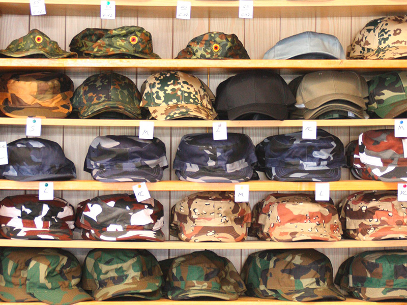Verschiedene Bundeswehr Caps und Mützen in unterschiedlichen Farben liegen übersichtlich in einem Regal in Hamm.