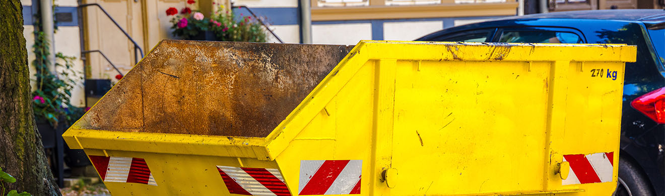 ein-gelber-absetzcontainer-steht-vor-einem-haus-in-hamm-auf-einer-baustelle