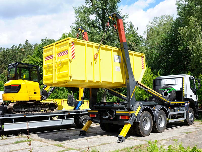 Unternehmen die Container vermieten in Hamm liefern gelben Container mit Containerfahrzeug auf die Baustelle