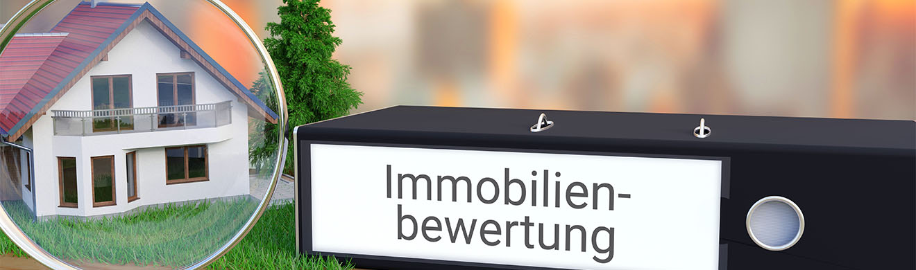 Immobilien bewerten in Hamm - ein Ordner Immobilienbewertung liegt neben einem Haus-Modell mit Lupe auf einem Schreibtisch