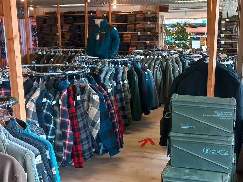 Ausstellungsraum mit Outdoor Bekleidung in Hamm, Jacken, Hemden und Schuhe auf Drehständern übersichtlich präsentiert.